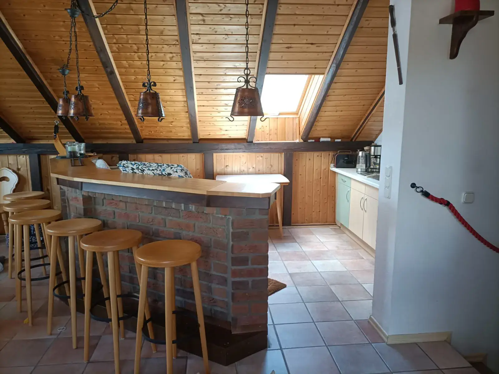 Dachgeschossraum mit Theke, Barhockern und Holzbalken